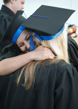 two graduates hugging